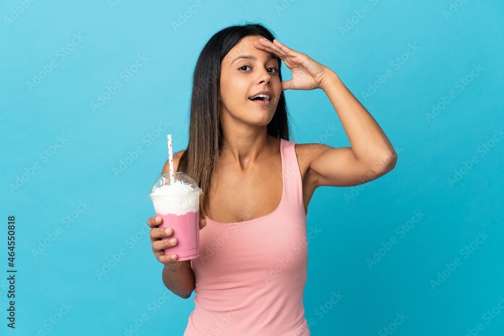 Young woman with strawberry milkshake doing surprise gesture while looking to the side Young woman with strawberry milkshake doing surprise gesture while looking to the side