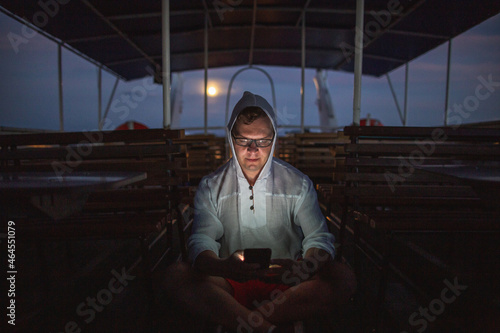 Dramatic night portrait of a man with a phone on an empty pleasure ship photo