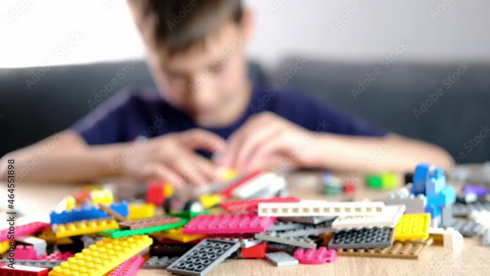 child, kid plays with colored plastic parts of the constructor, creates buildings, equipment, transport, the concept of the development of creativity, fine motor skills, patience and perseverance child, kid plays with colored plastic parts of the constructor, creates buildings, equipment, transport, the concept of the development of creativity, fine motor skills, patience and perseverance