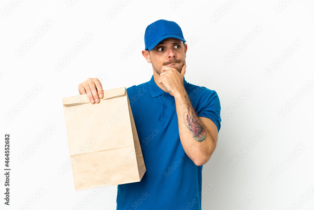 Brazilian taking a bag of takeaway food isolated on white background having doubts and thinking Brazilian taking a bag of takeaway food isolated on white background having doubts and thinking