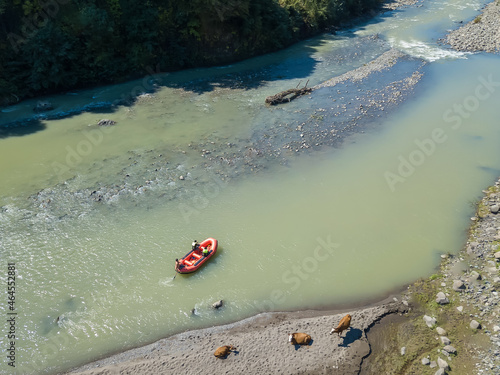 Drone view of a boat sailing along a mountain river among the mountains on a sunny day in Georgia