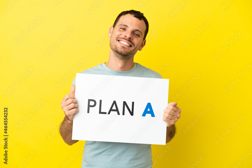 Brazilian man over isolated purple background holding a placard with the message PLAN A Brazilian man over isolated purple background holding a placard with the message PLAN A