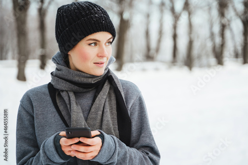 Woman athlete using smartphone during her winter workout in snowy city park © blackday
