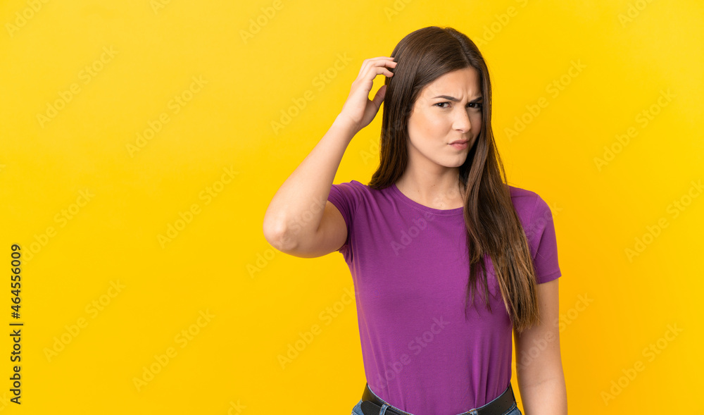 Teenager Brazilian girl over isolated yellow background having doubts Teenager Brazilian girl over isolated yellow background having doubts