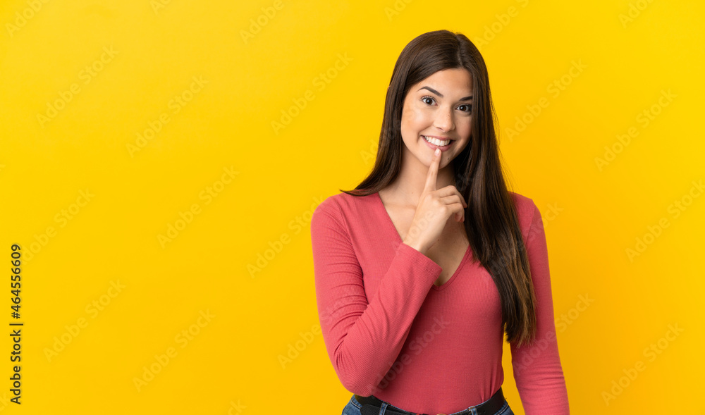 Obraz premium Teenager Brazilian girl over isolated yellow background showing a sign of silence gesture putting finger in mouth