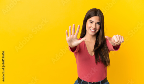 Teenager Brazilian girl over isolated yellow background counting six with fingers