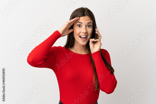 Teenager Brazilian girl using mobile phone over isolated white background with surprise expression