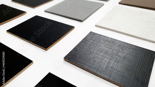 perspective view of multi surface of melamine samples in black color and multi color of grainy artificial stone samples for selection placed on white paper background (focused at fabric texture). photo