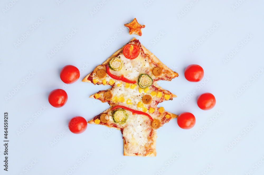 Delicious vegetarian Christmas tree pizza with tomatoes, vegetables and cheese on blue background. Creative, funny food concept for kids. Top view, flat lay. Copy space. Template. Mock up.