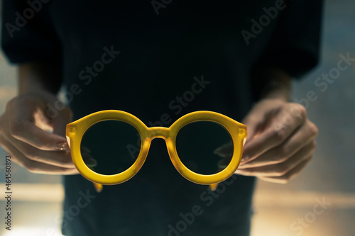 Close of young teenager girl holding a pais of yellow sunglasses with both hands rediscovering outdoors after covid lockdown.  Youth freedom post pandemic feel. photo