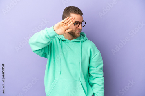 Young handsome caucasian man isolated on purple background making stop gesture and disappointed © luismolinero