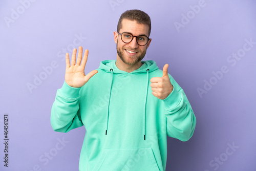 Young handsome caucasian man isolated on purple background counting six with fingers © luismolinero
