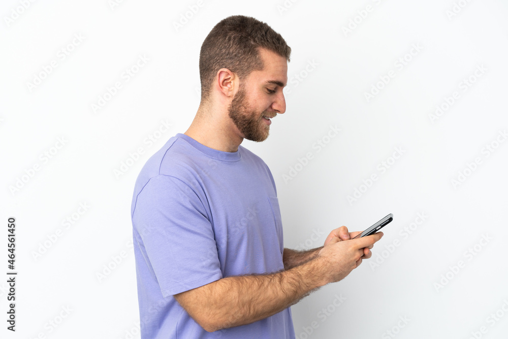 Young handsome caucasian man isolated on white background sending a message or email with the mobile Young handsome caucasian man isolated on white background sending a message or email with the mobile