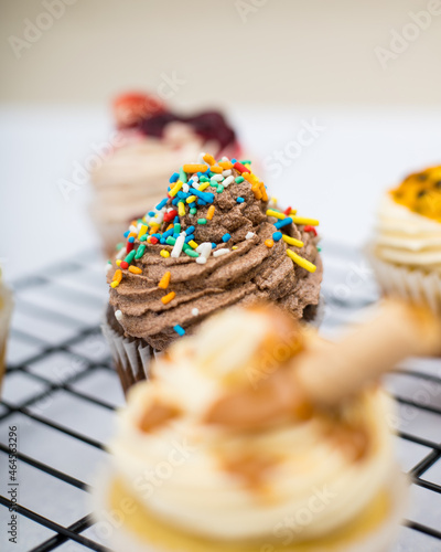 black cupcake decorated with a piping bag chocolate cream and sprinkles