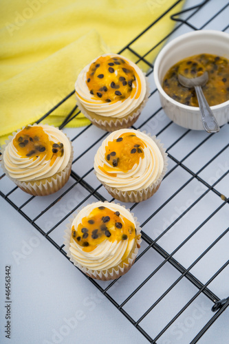 passion fruit cupcake decorated by a piping bag white cream on a grid and a marble background