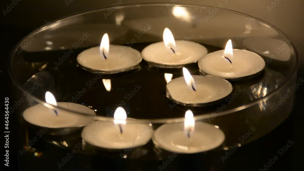 Close up of several floating candles in a glass of water. Beautiful candle light. Atmosphere of romance and love. Close up of several floating candles in a glass of water. Beautiful candle light. Atmosphere of romance and love.
