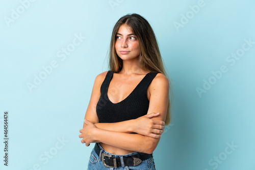 Young caucasian woman isolated on blue background looking to the side