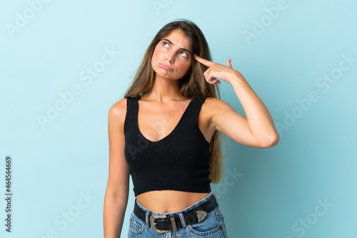 Young caucasian woman isolated on blue background making the gesture of madness putting finger on the head © luismolinero