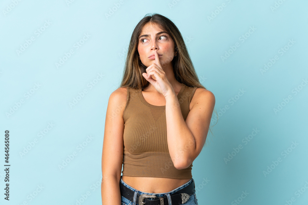 Young caucasian woman isolated on blue background showing a sign of silence gesture putting finger in mouth Young caucasian woman isolated on blue background showing a sign of silence gesture putting finger in mouth