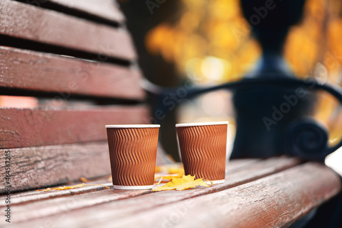 Obraz na płótnie Two paper cups of coffee on wooden bench in autumn park on sunny day. Coffee time. w salonie