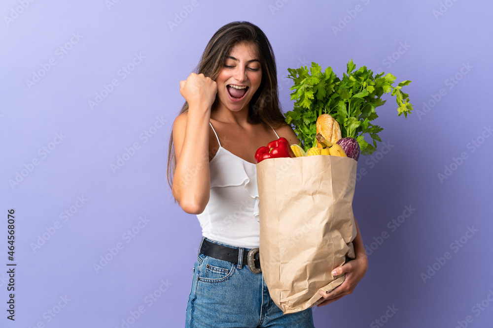 Young woman holding a grocery shopping bag celebrating a victory Young woman holding a grocery shopping bag celebrating a victory