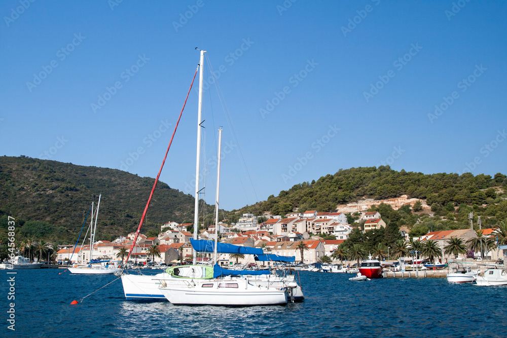 Ships mooring in the marina at the beautiful town with red roof tiles on houses near mountain