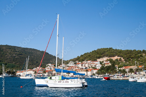 Ships mooring in the marina at the beautiful town with red roof tiles on houses near mountain