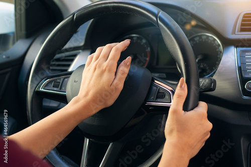 Close up of woman hand pressing the horn button while driving a car. aggressive driver using horn © Ken