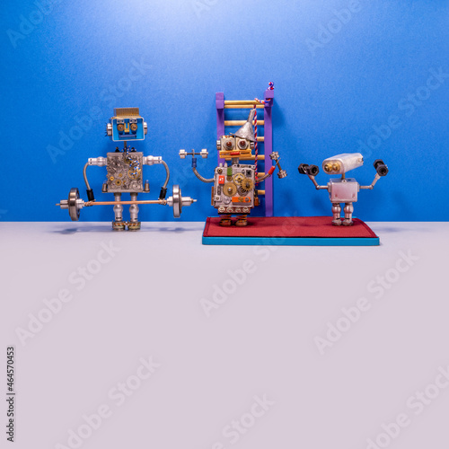 Robot weightlifters work with a barbell and dumbbells. Toy workout gym wall bars on a blue-gray background. Power sport, fitness and weightlifting concept