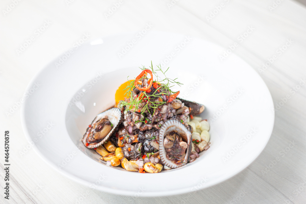 Black ceviche with shell, very typical in Peru. on white plate.
