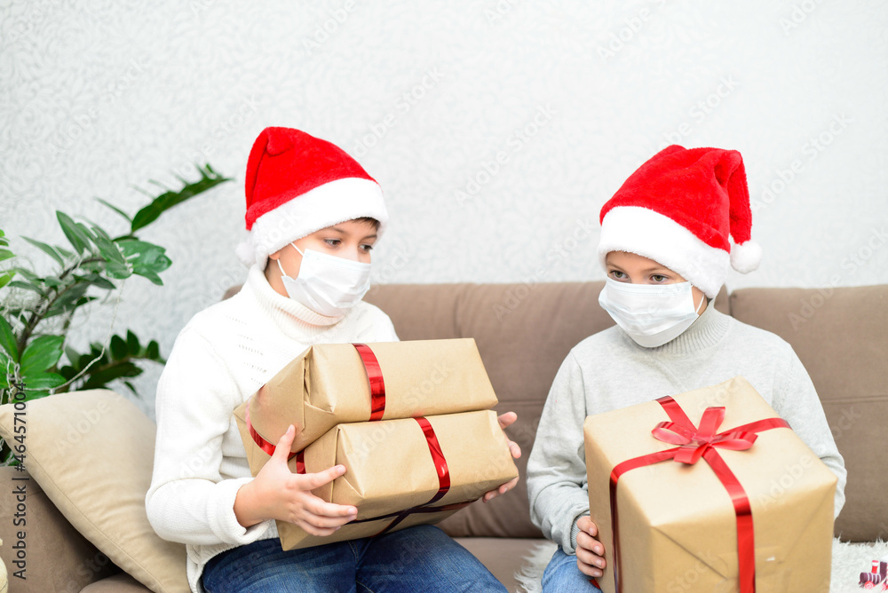 Two boys are holding his christmas presents. They are in the masks. Coronovirus. Horizontal frame. Two boys are holding his christmas presents. They are in the masks. Coronovirus. Horizontal frame.