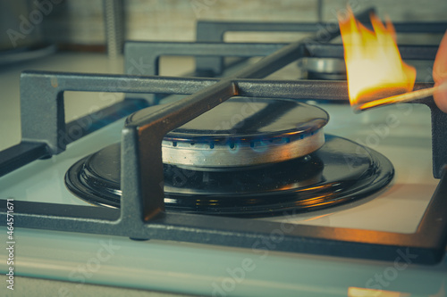 A man lights a gas stove with a match .