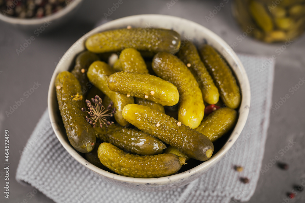 Plate of gherkins, pickled cucumbers on a grey concrete background