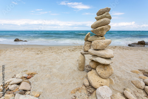 Zen stones stack balanced on beach with sea and clear blue sky in background