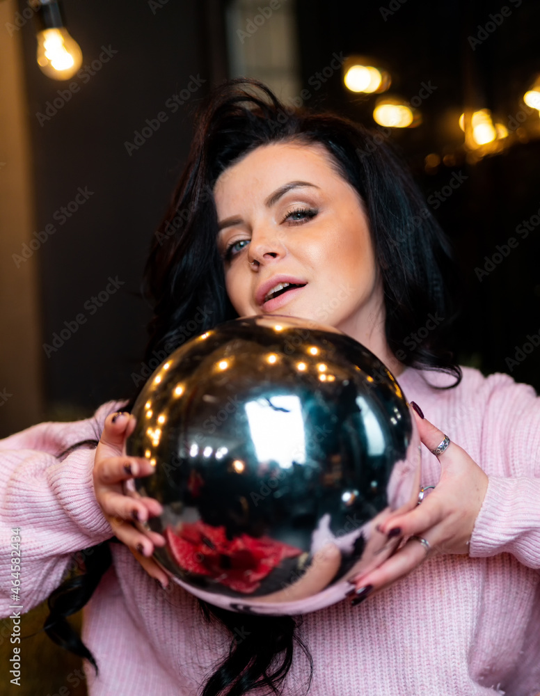 Naklejka premium Beautiful attractive female with christmas ball. Pretty woman in sweater posing with christmas ball.