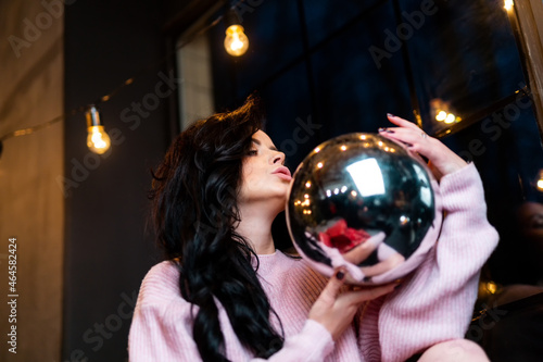 Pretty woman in sweater posing with christmas ball. Beautiful attractive female with christmas ball.