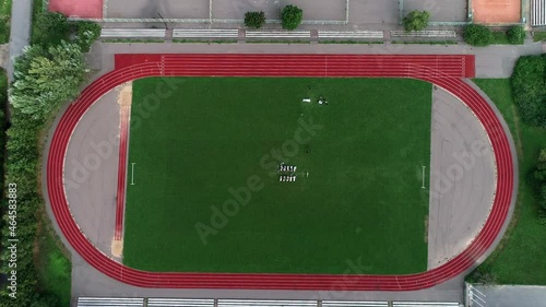 Wedding exit ceremony at the football running sports stadium. Wedding white decor arch chairs for guests on the grass. Wedding on the green field. A drone shot. View from the top
