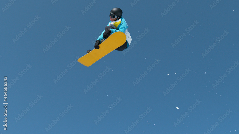 Athletic snowboarder jumps high into the air and performs an extreme grab trick. Athletic snowboarder jumps high into the air and performs an extreme grab trick.