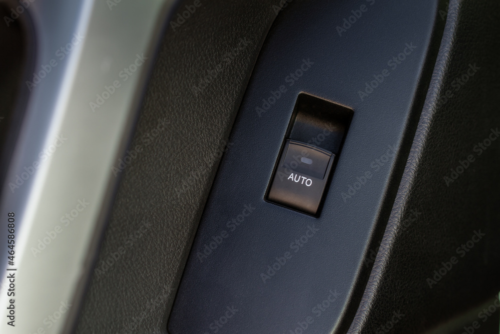 Car door handle with power window control. Dark leather interior of modern car. Dark black and orange car leather pleats stitch. Details of door handle with windows controls. Car window controls. Car door handle with power window control. Dark leather interior of modern car. Dark black and orange car leather pleats stitch. Details of door handle with windows controls. Car window controls.