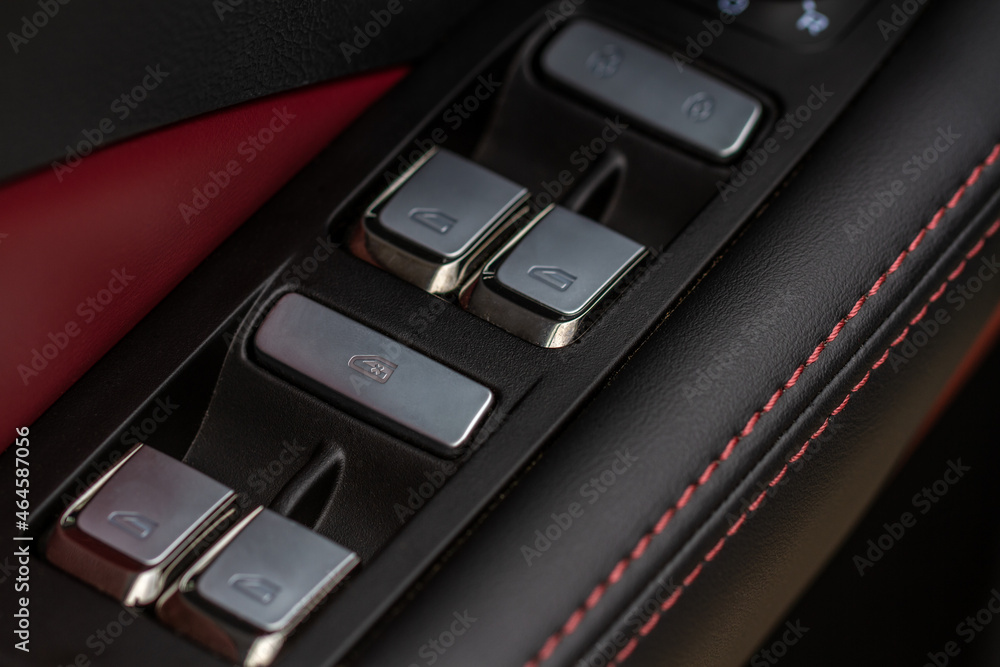 Obraz premium Close up view of button controlling window in modern car interior. Vehicle interior detail. Door handle with windows controls