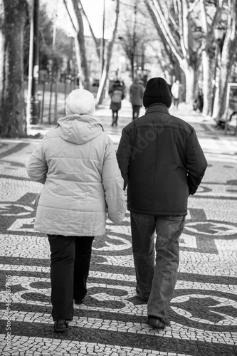 Senior portuguese couple walking on the Av. da Liberdade pedestrian avenue in central Lisbon with cobblestone pavement