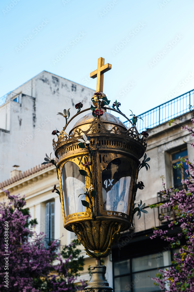 Beautiful golden streetl lampost with crucifix cross on top on in front of Agia Paraskevi Church on the pedestrian part of Aiolou street