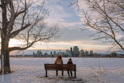 Mother and son sitting on a bench in a snowy field in Calgary, Alberta
