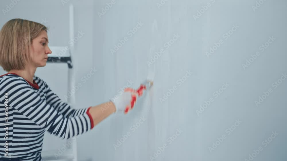 Woman worker using a brush painting walls in the apartment or house. Construction, repair and renovation Woman worker using a brush painting walls in the apartment or house. Construction, repair and renovation