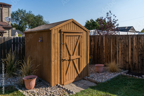 A backyard tool shed with a wooden fence.