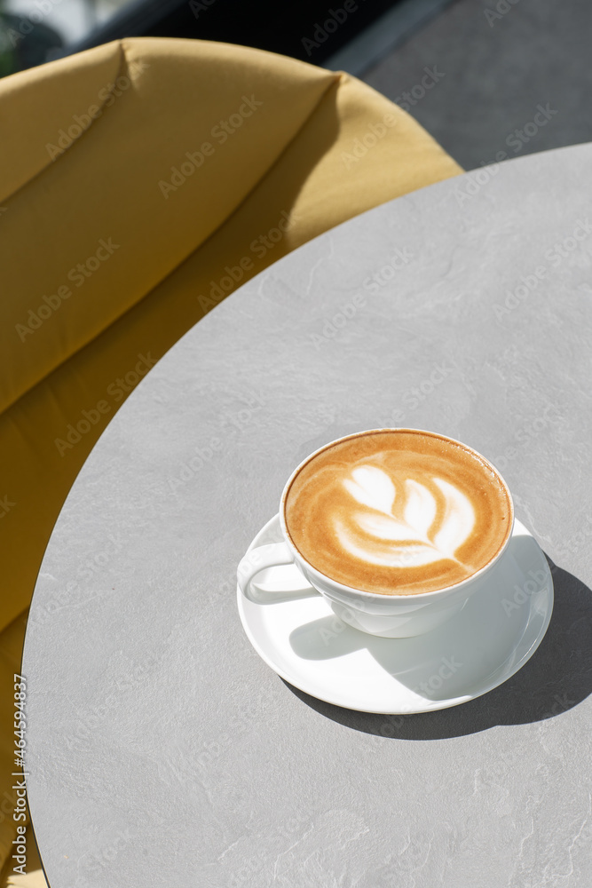 White cup of hot latte coffee with beautiful milk foam latte art texture isolated on gray background. Overhead view, copy space. Advertising for cafe menu. Coffee shop menu.
