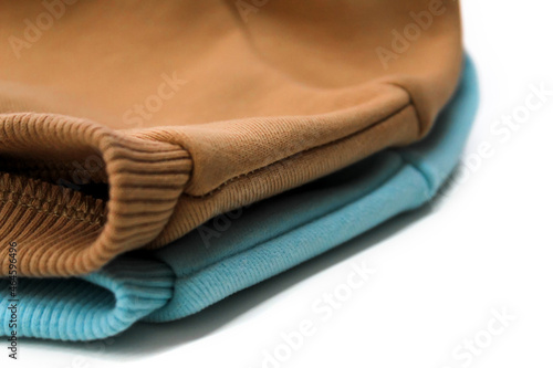 Two sweatshirts of blue and ochre color close-up, turned to us with a shoulder seam. Concept: atelier, clothing store brand, cutting and sewing courses, sewing hobby.