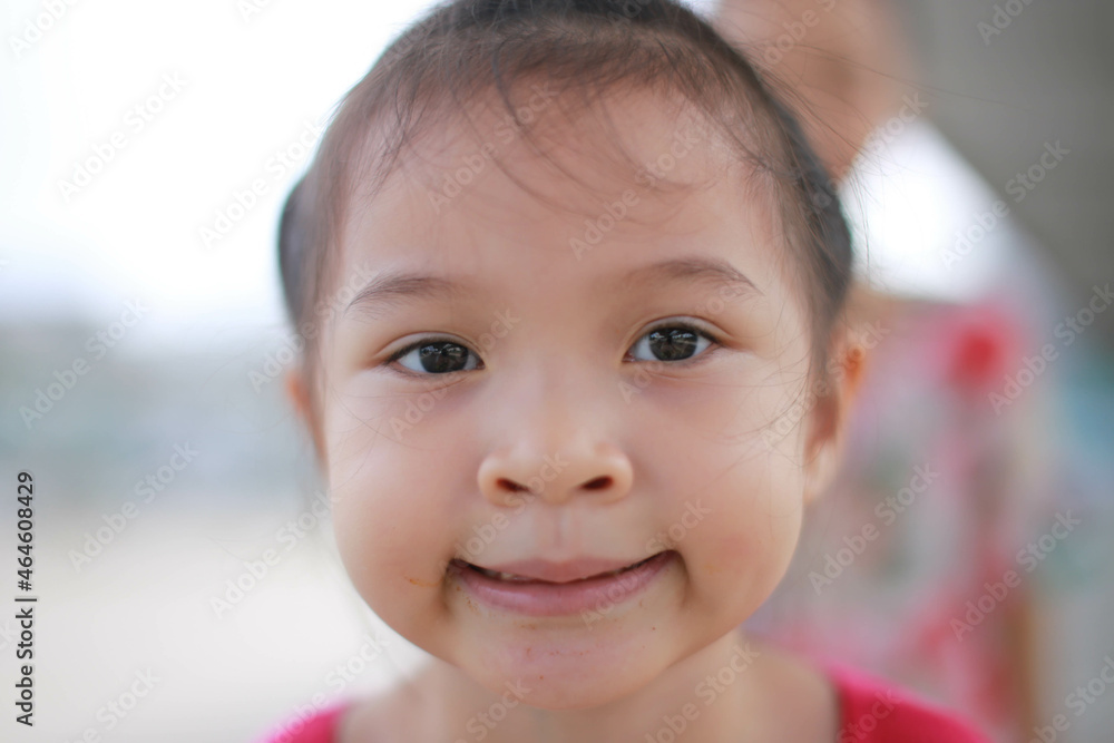 Happy Little asian girl child showing front teeth with big smile and laughing