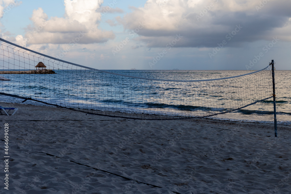 Fototapeta premium filet de volleyball sur une plage déserte avec vue sur la mer au matin et des nuages dans le ciel