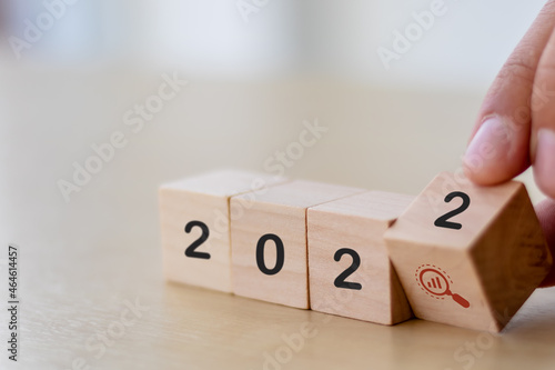 2022 forecast concept of economy, business, sales, finance for business plan and development. Hand flips wooden cubes "2022" and "magnifying glass" symbol on beautiful background and copy space